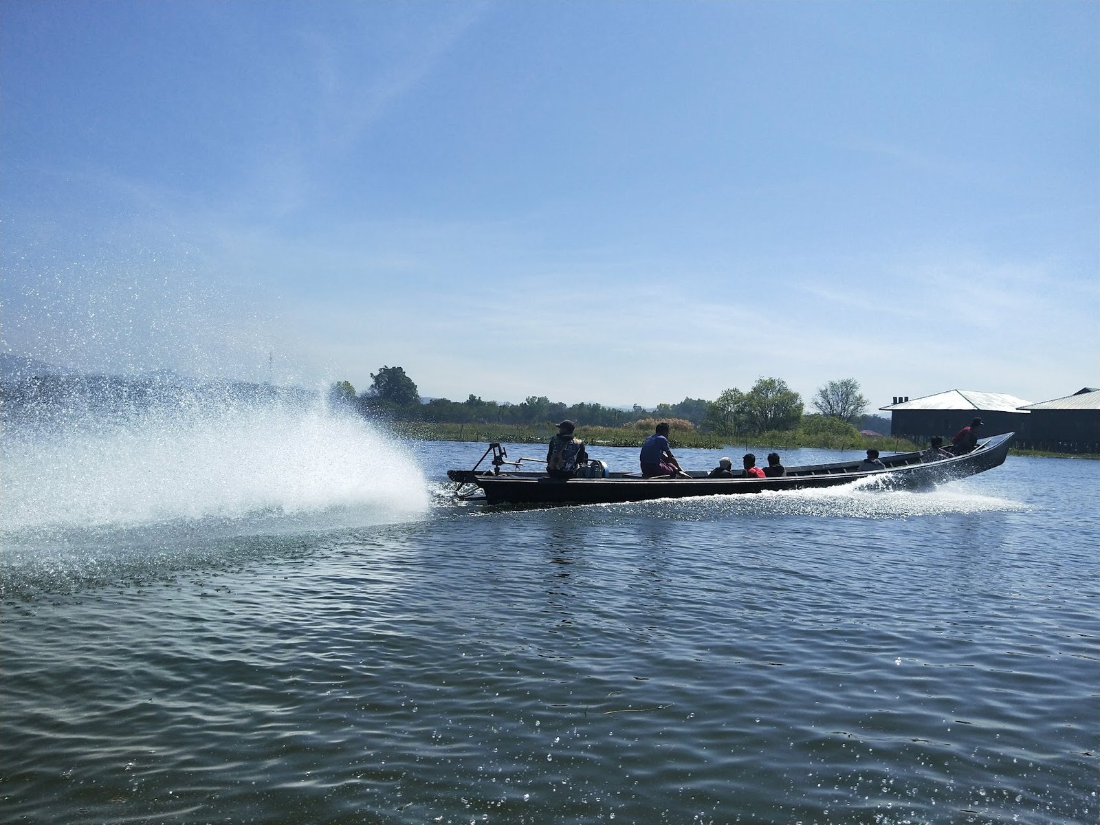 Tourists in a long-tail boat on Inle Lake, Myanmar. A powerful outboard engine propels the screw, which is on a long pole so it can easily be lifted out of the water to avoid weed snags.